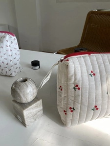 Detail of quilted cotton cosmetic bags with cherry and floral prints and ribbon zippers