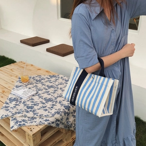 Détail du sac cabas en toile rayée bleue avec poignées imprimées et fermoir métallique