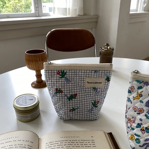 Trousse à maquillage matelassée à fleurs avec fermeture éclair sur une table blanche