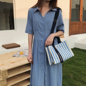 Détail d'un sac cabas en toile rayée avec bandoulière GOODLUCK et robe bleu clair