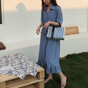 Sac cabas en toile rayé bleu et blanc avec sangle GOODLUCK dans un décor d'été en plein air