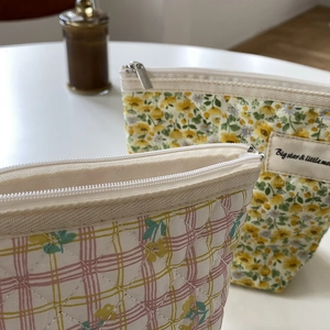 Détail de trousses à maquillage matelassées à fleurs et à carreaux avec fermeture éclair en métal