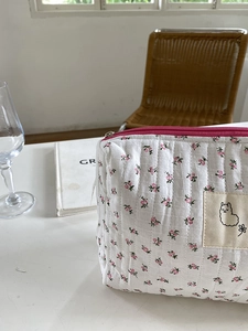 Detailed shot of quilted floral cosmetic bag with pink zipper and cute alpaca label