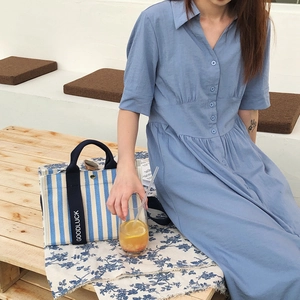 Sac fourre-tout en toile à rayures bleu et blanc avec poignée Goodluck sur table en bois