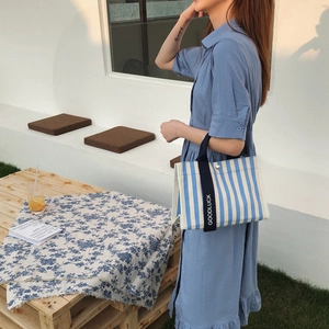 Sac cabas en toile à rayures bleues et blanches avec anses Goodluck tenu par un mannequin
