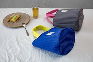 Détail du sac à main en coton matelassé montrant la texture douce et les anses contrastées