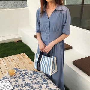 Détail du sac fourre-tout en toile à rayures bleu et blanc avec sangle Goodluck sur un mannequin