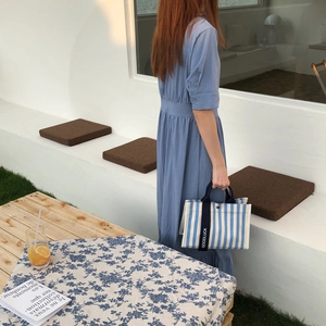 Détail du sac cabas en toile rayé bleu et blanc avec bandoulière Goodluck sur table