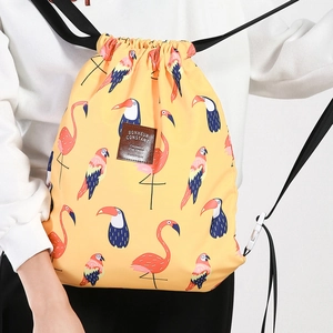 Detail eines gelben Kordelzug-Rucksacks mit tropischen Flamingo- und Tukan-Mustern