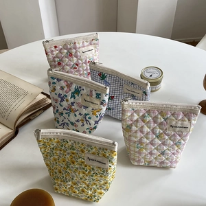 Lot de 5 trousses de maquillage en coton matelassé aux motifs floraux sur une table blanche