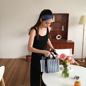 Détail d'un sac cabas en toile à rayures bleues avec bandoulière et texte GOODLUCK