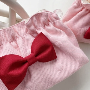 Detail of pink waffle fabric texture with a red bow and pleated ruffled edge detail