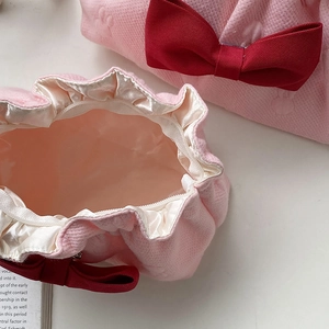Close-up of pink bow makeup bag featuring soft knit texture and smooth satin lining