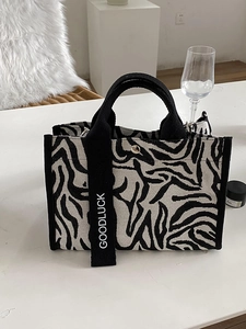 Détail du sac cabas en toile zébrée avec sangle 'GOODLUCK' et bouton pression argenté