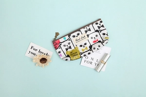 Detail eines Canvas-Etuis mit Katzen-Prints und Good Luck-Tag auf blauem Hintergrund