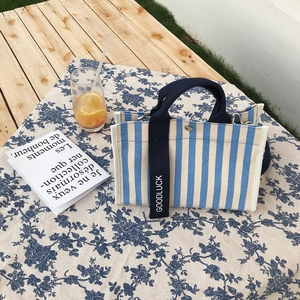 Sac fourre-tout en toile à rayures bleues et blanches sur une table de pique-nique