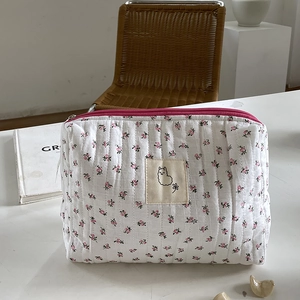 Quilted floral cosmetic bag with cute alpaca patch and pink zipper in a home setting