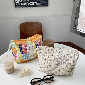 Quilted cosmetic bags in floral and cherry patterns on a white table with lifestyle props
