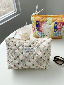 Close-up of quilted floral cosmetic bags with ribbon zippers on a white desk