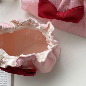 Pink quilted bow makeup bag with red ribbon accent and spacious satin lining interior