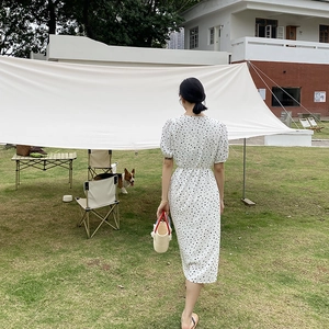 Vestido midi de lunares con mangas abullonadas y un bolso de cubo tejido al aire libre