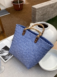 Detail der blauen Flechtasche mit Bambusgriffen auf einem dekorativen Außentisch