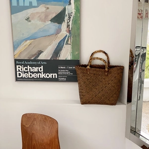 Detailansicht einer Vintage-Geflochtene Tasche mit Bambusgriff auf einem eleganten Sims