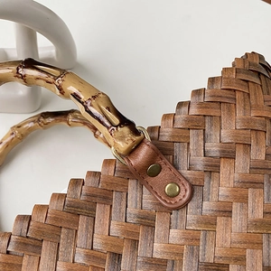 Detailaufnahme der gewebten Retro-Tasche mit Bambusgriff und Lederbesatz mit Nieten