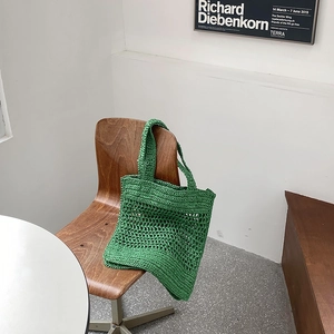 Primer plano de un bolso de ganchillo verde en silla vintage con diseño de malla calada