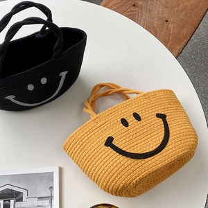 Detailed top view of woven cotton rope beach bags with cute smiley faces in black and yellow