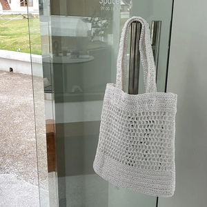 Detalle del bolso tote de malla tejida blanca que muestra los complejos patrones de nudos