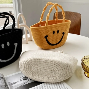 Detail of woven cotton rope beach bag with embroidered smiley face in various colors