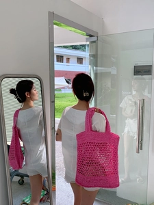 Primer plano de bolsa de playa de ganchillo rosa brillante con textura tejida
