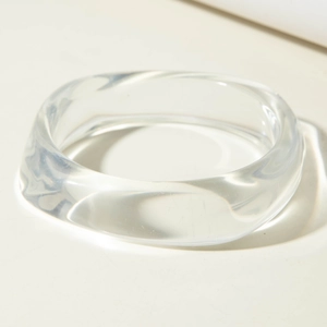 Gros plan d'un bracelet large en résine translucide au design ondulé irrégulier