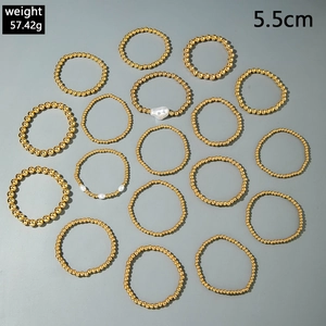 Detaillierte Flachbildaufnahme von vergoldeten Perlenarmbändern mit weißen Perlen auf Grau