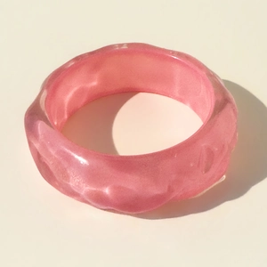 Macro detail of pink resin bangle with water ripple texture and sparkling glitter finish
