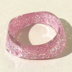 Close-up of pink resin bangle with sparkling glitter and subtle water ripple effect