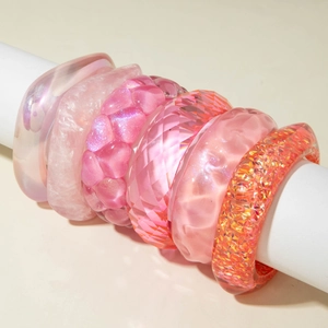 Set of 6 pink resin bangles with heart relief and glitter finish on a white stand