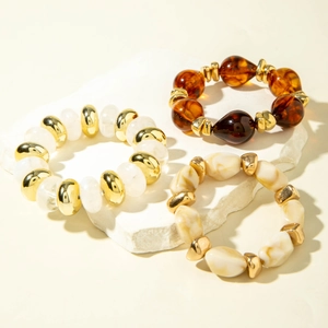 Close-up of three stacked retro acrylic beaded bracelets on a white stone pedestal