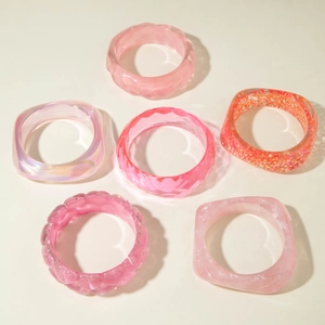 Macro detail of 6-piece pink resin bracelet set with glitter and ripple textures