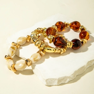 Detail of amber acrylic and cream textured bead bracelets on white stone tray
