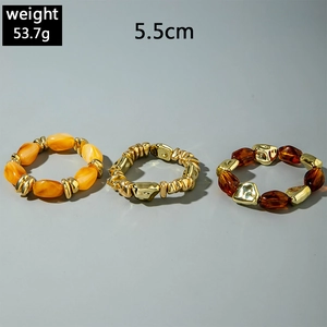 Detailed view of layered acrylic bead bracelets with golden alloy accents in amber tones