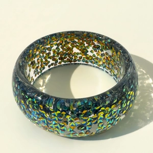 Macro shot of colorful iridescent glitter fragments inside a wide resin chunky bangle