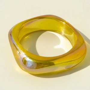 Macro detail of amber resin square bangle showing iridescent laser finish and smooth edges