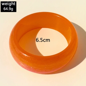 Détail d'un bracelet en résine ambre pailletée avec 6,5 cm de diamètre et 64,9 g de poids