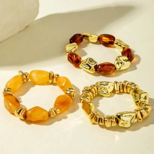 Macro detail of three-piece bohemian stretch bracelet set with amber resin and gold beads