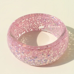 Close-up of pink resin bangle with sparkling glitter particles in bright lighting