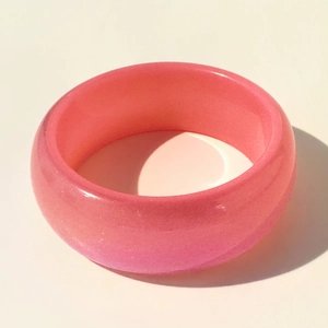 Détail macro du bracelet en résine rose pailleté avec surface lisse et fini perlé