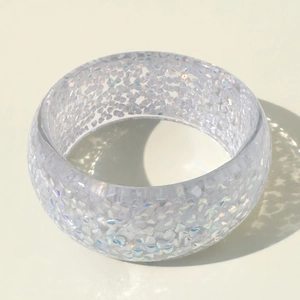Detailed view of colorful resin bangle with sparkling glitter and artistic shadows