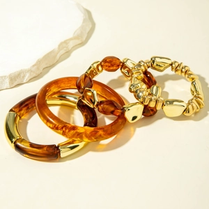 Close-up of retro amber resin bangles and gold chain bracelet set on stone background